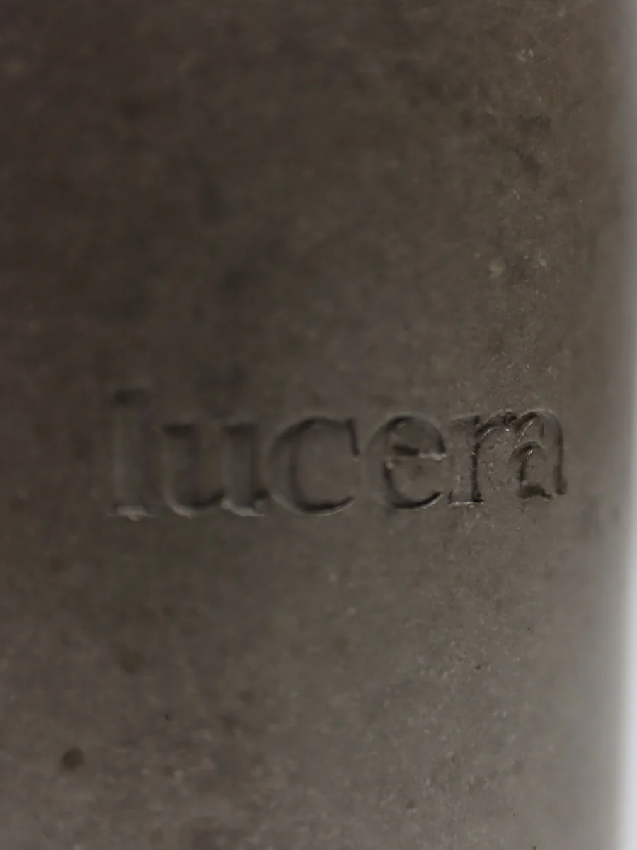 Detail vyraženého loga lucera v ručně litém betonu